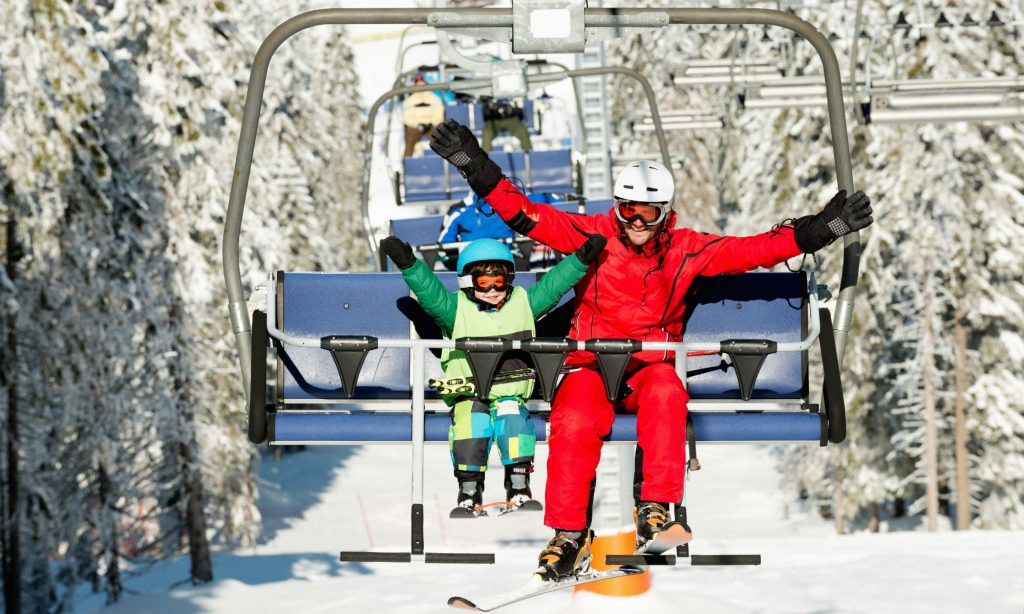Wie Kinder Skifahren lernen: Ein kleines Kind und sein Skilehrer fahren mit dem Lift.