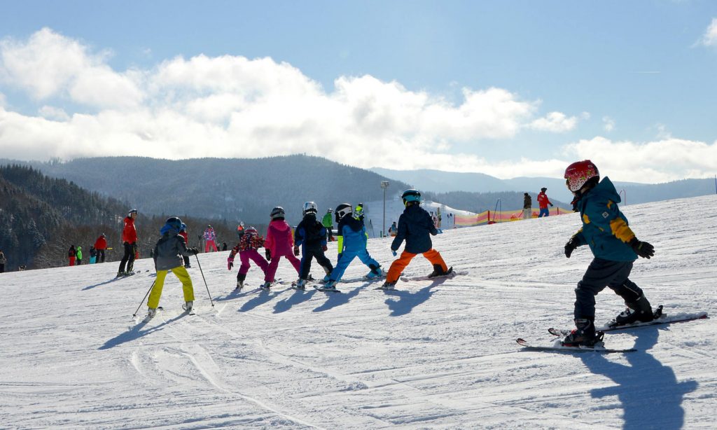 Eine Gruppe Kinder beim Skifahren lernen auf der Piste.